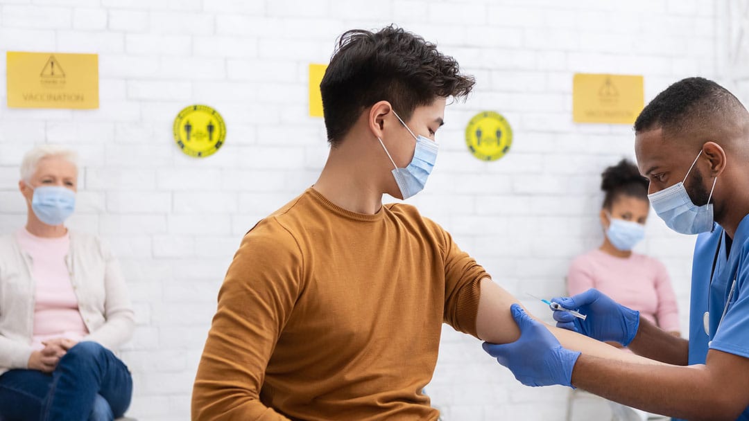 Male news performing vaccination on a patient in a clinic