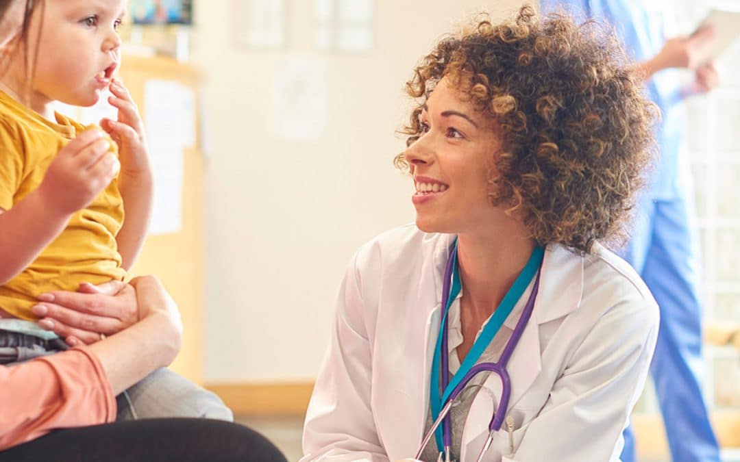 Female doctor speaking to young boy with family