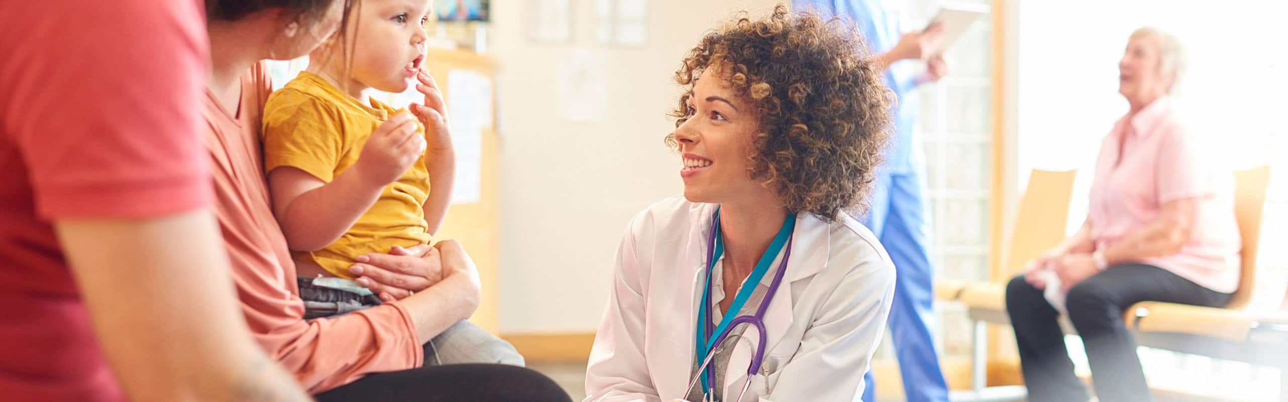 Female doctor speaking to young boy with family